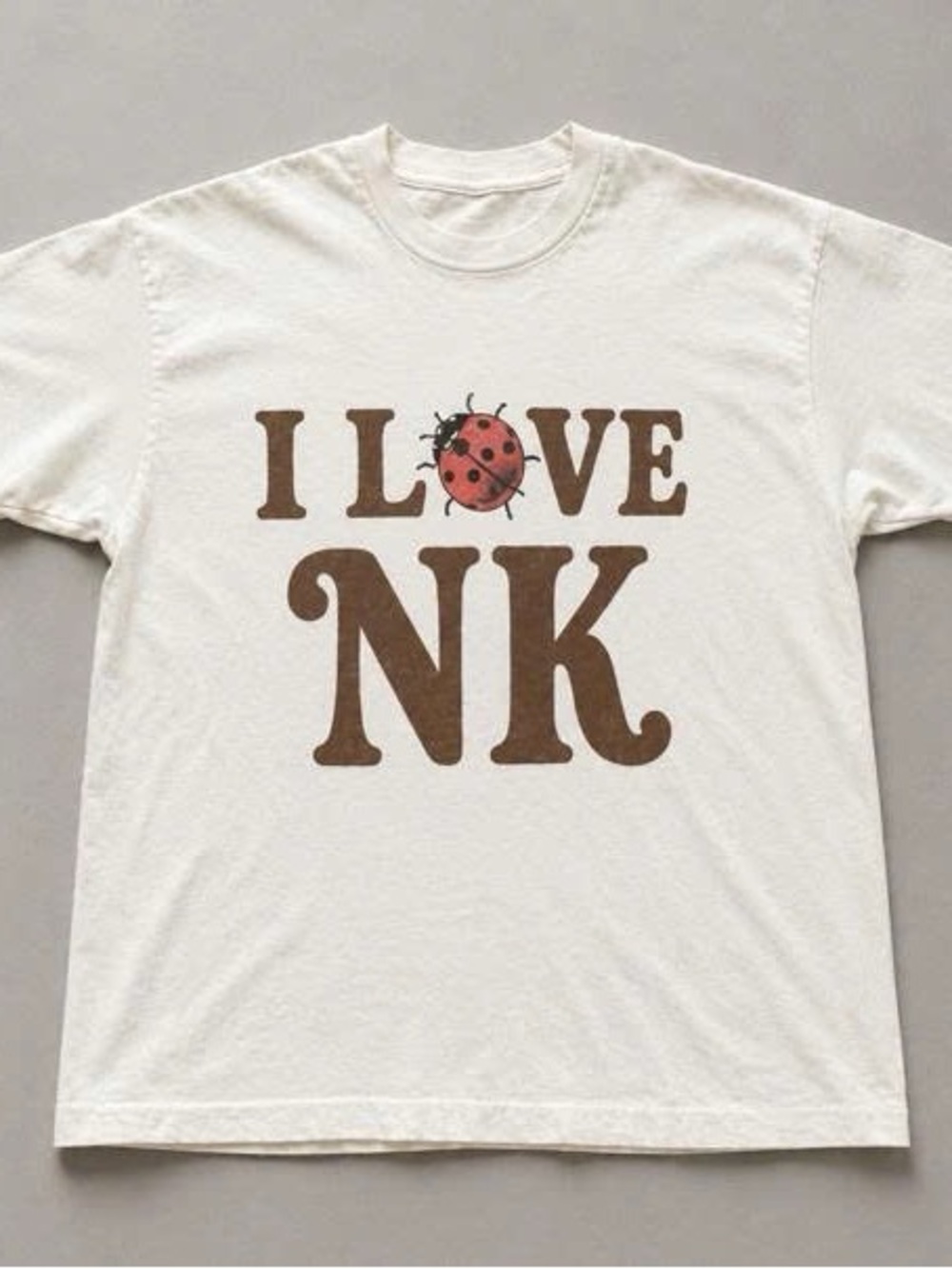 Cream Short Sleeve Tee with Brown Text and Red Ladybug